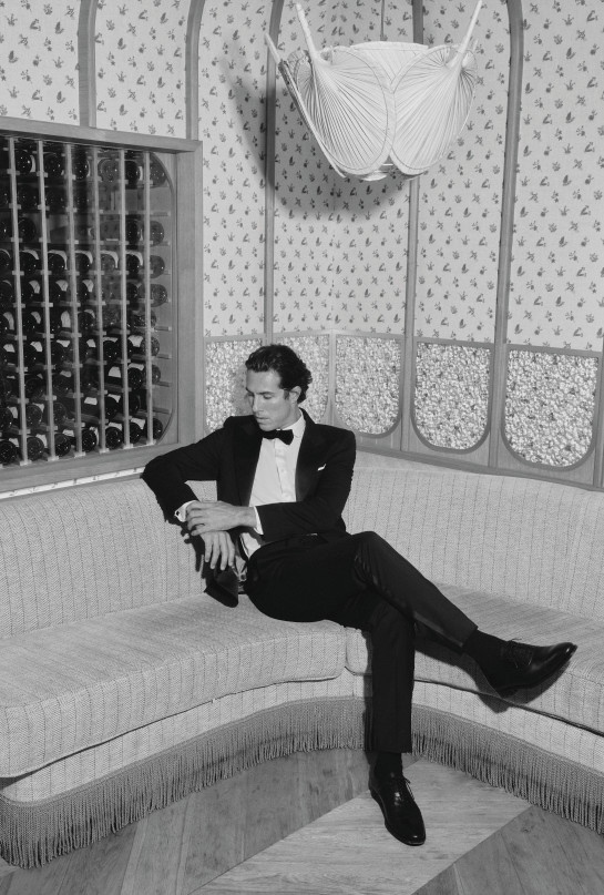 foto en blanco y negro de modelo con smooking sentado en un restaurante